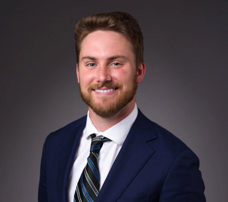 A smiling man with a beard wearing a tie, exuding confidence and professionalism.